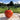 One Ailsa Craig salad tomato against a backdrop of trees and field
