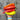Hand holding a bunch of red, orange, and yellow peppers against a wooden background
