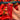 Hand holding a red pepper amidst a large pile of red peppers.